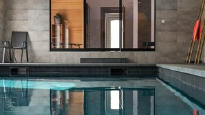 Una piscina interior moderna con vista despejada de la estructura del techo y un ventanal grande.