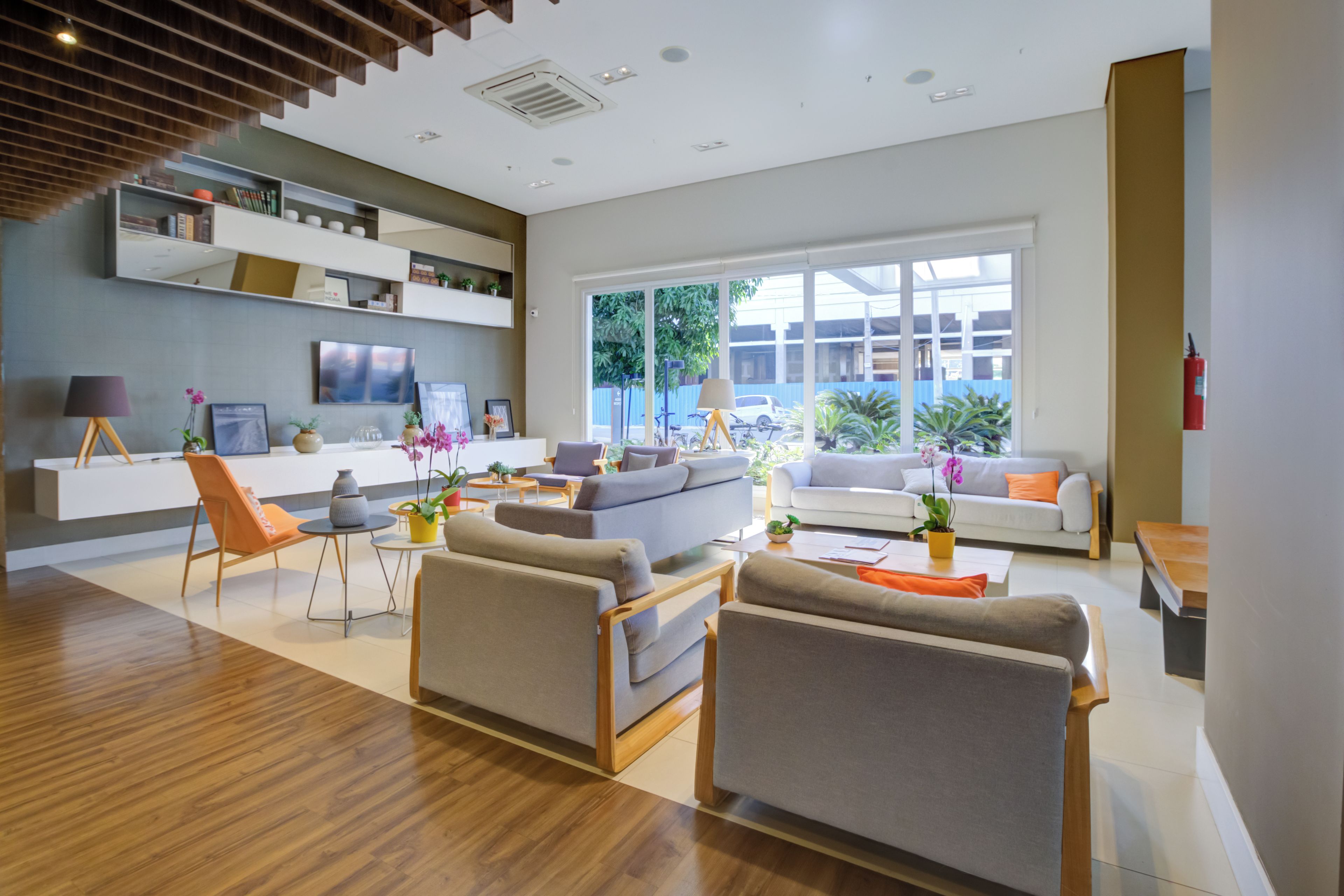 Uma sala de estar moderna com um sofá, poltronas, uma mesa de centro e uma televisão.