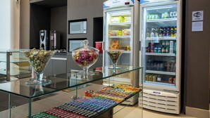 A hotel lobby with a glass display case containing various snacks and a Travel Inn refrigerator stocked with beverages.