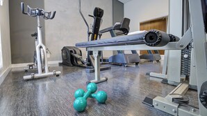 Une salle de sport équipée de divers appareils, notamment un tapis de course, un vélo elliptique et des poids.