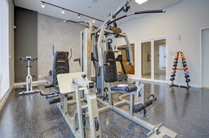 Une salle de sport équipée de divers appareils d’entraînement, notamment un support à squats, un banc de développé couché et une machine à câbles.