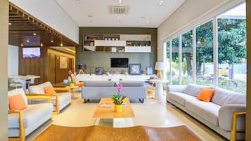 A modern living room with sofas, a coffee table, and a TV mounted on the wall.