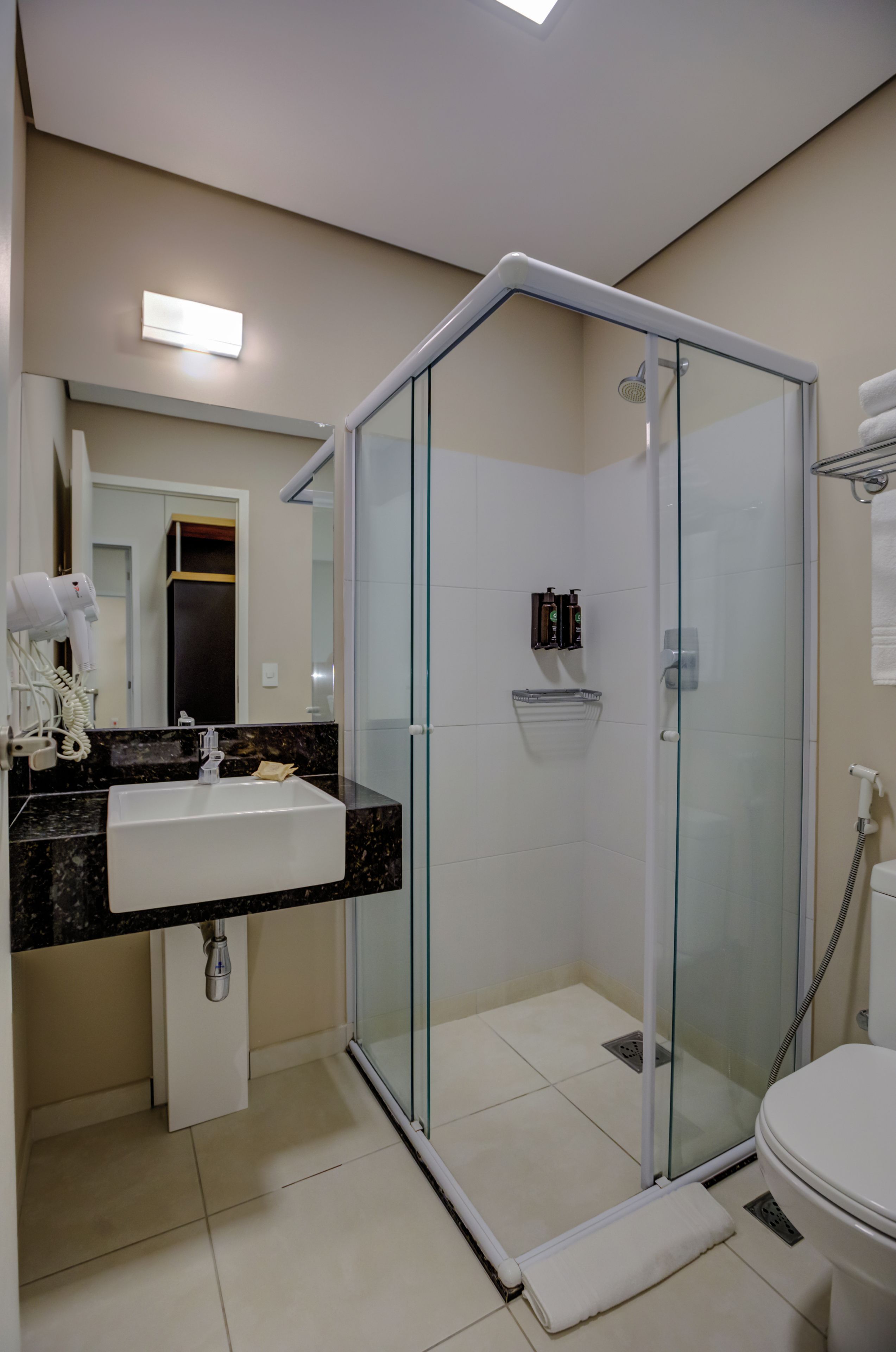 Un baño moderno con ducha de vidrio, un lavamanos con encimera de mármol y un inodoro.