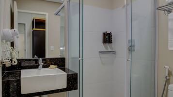 Un baño moderno con ducha de vidrio, un lavamanos con encimera de mármol y un inodoro.