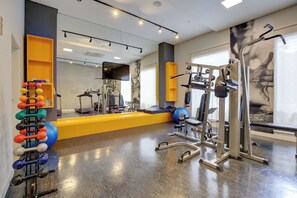 A gym with various exercise equipment, a mirror, and a wall-mounted TV. - Transamerica Wise Indaiatuba (Indaiatuba)