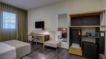 A hotel room with a bed, a desk, a chair, a television, a wardrobe, and a microwave.