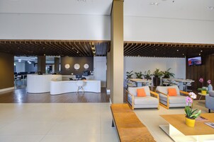 Una moderna recepción con un mostrador curvo, asientos y una pantalla de televisión.