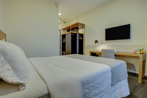 Ein Hotelzimmer mit Bett, Schreibtisch, Stuhl, Fernseher und Kleiderschrank.