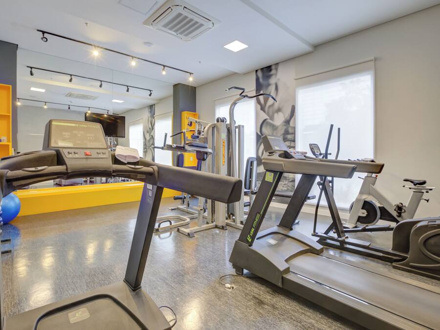 Una palestra con tapis roulant, attrezzi per esercizi e una grande finestra.