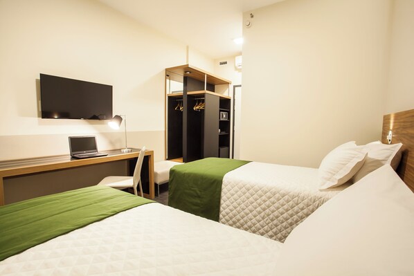 A hotel room with two beds, a desk with a laptop, a TV, and a wardrobe. - Transamerica Wise Indaiatuba (Indaiatuba)