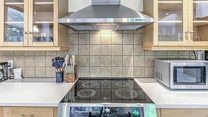 Cucina con cappa in acciaio inossidabile, forno a microonde e mobili in legno.