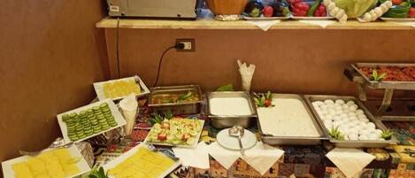A buffet table with various food items and a television on a stand.