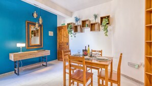 A dining area with a wooden table set for four, a bench with a lamp, and a mirror on the wall. - Charming 2-Bedroom Apartment with Balconies MGAJ1-1 (Msida)