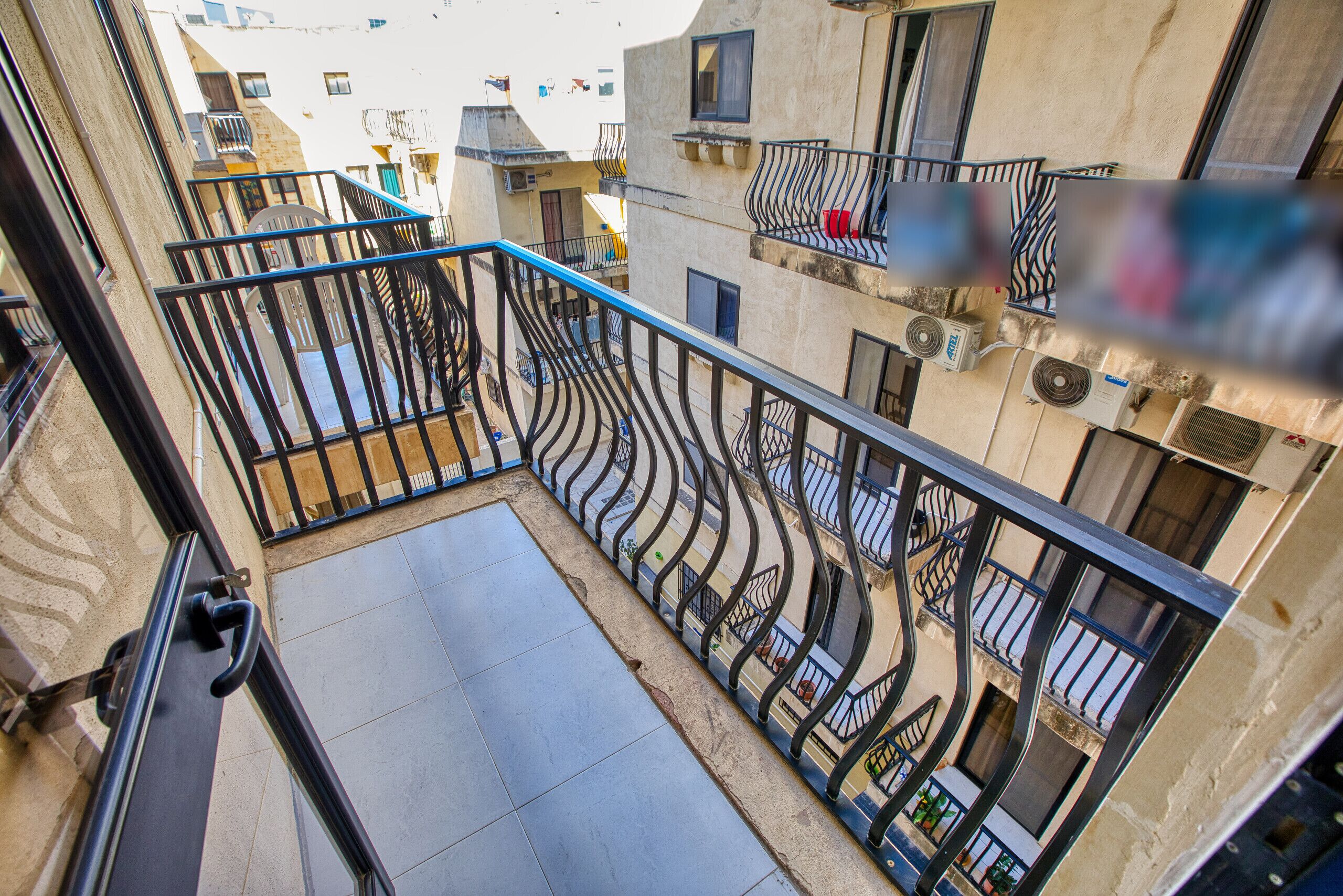 Un immeuble résidentiel à plusieurs étages, doté de balcons, d’un escalier et offrant une vue sur les bâtiments voisins.
