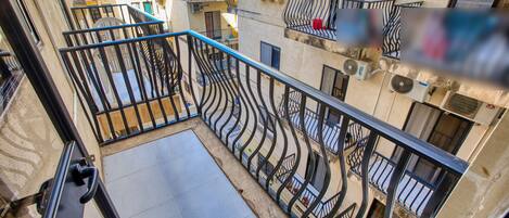 Un immeuble résidentiel à plusieurs étages, doté de balcons, d’un escalier et offrant une vue sur les bâtiments voisins.