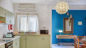 A kitchen with a microwave, toaster, and sink. There is a dining table with chairs and a hanging light fixture. - Charming 2-Bedroom Apartment with Balconies MGAJ1-1 (Msida)