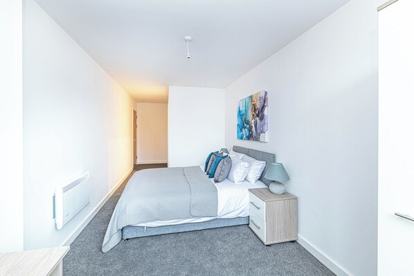 A modern bedroom with a bed, bedside table, and a painting on the wall.