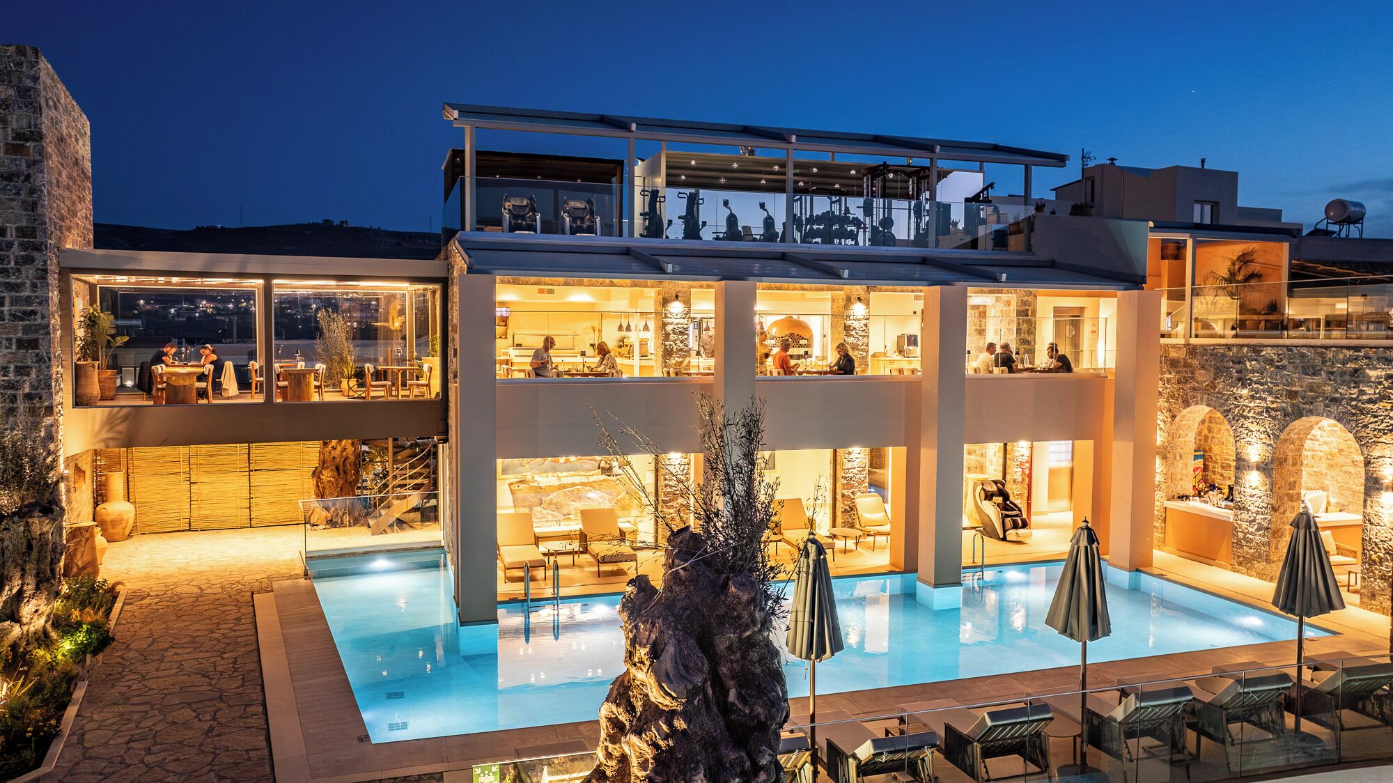A multi-story hotel with a pool, outdoor seating, and a stone facade.