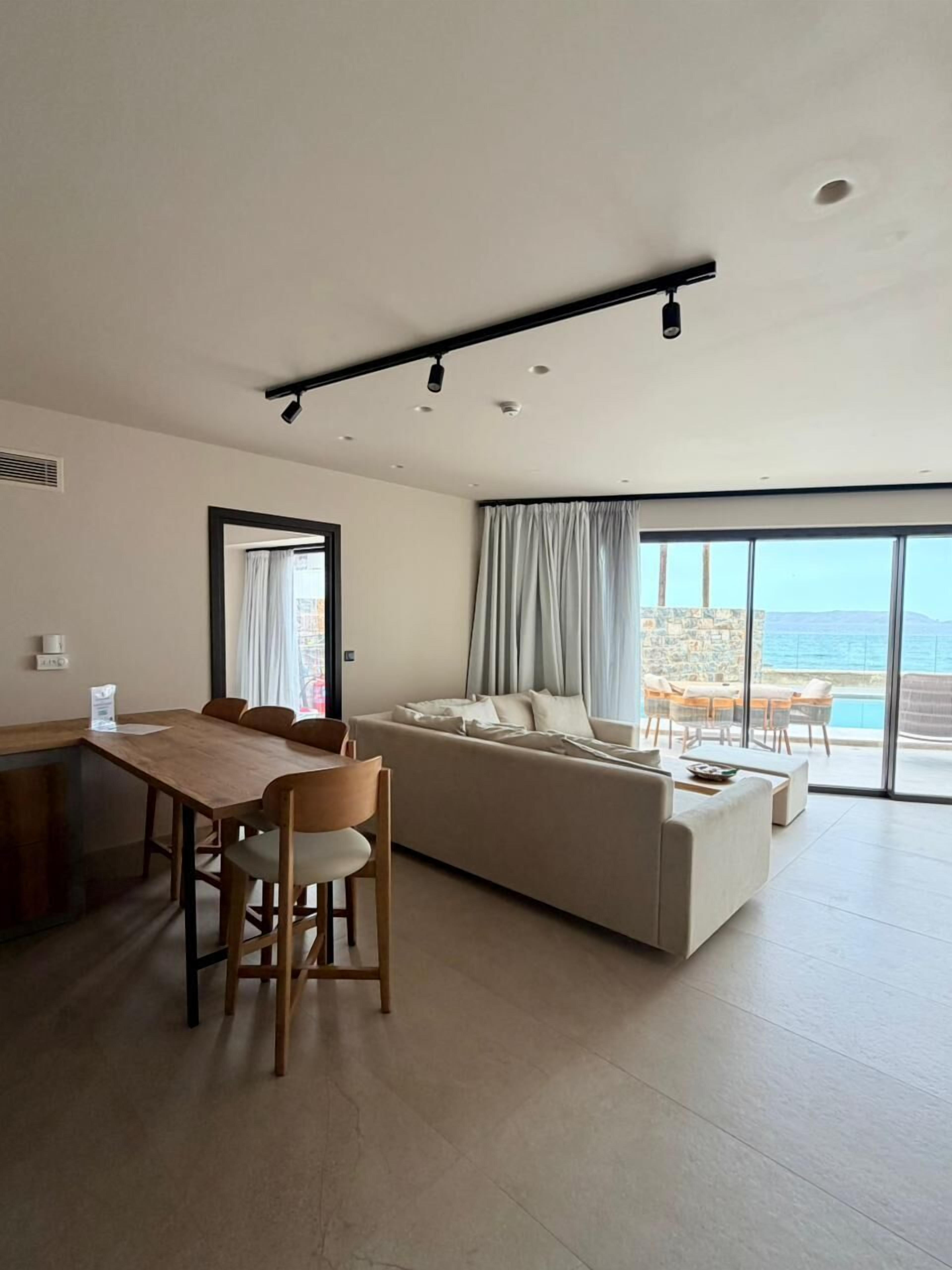 Ein modernes Wohnzimmer mit Essbereich, großen Fenstern und Meerblick.
