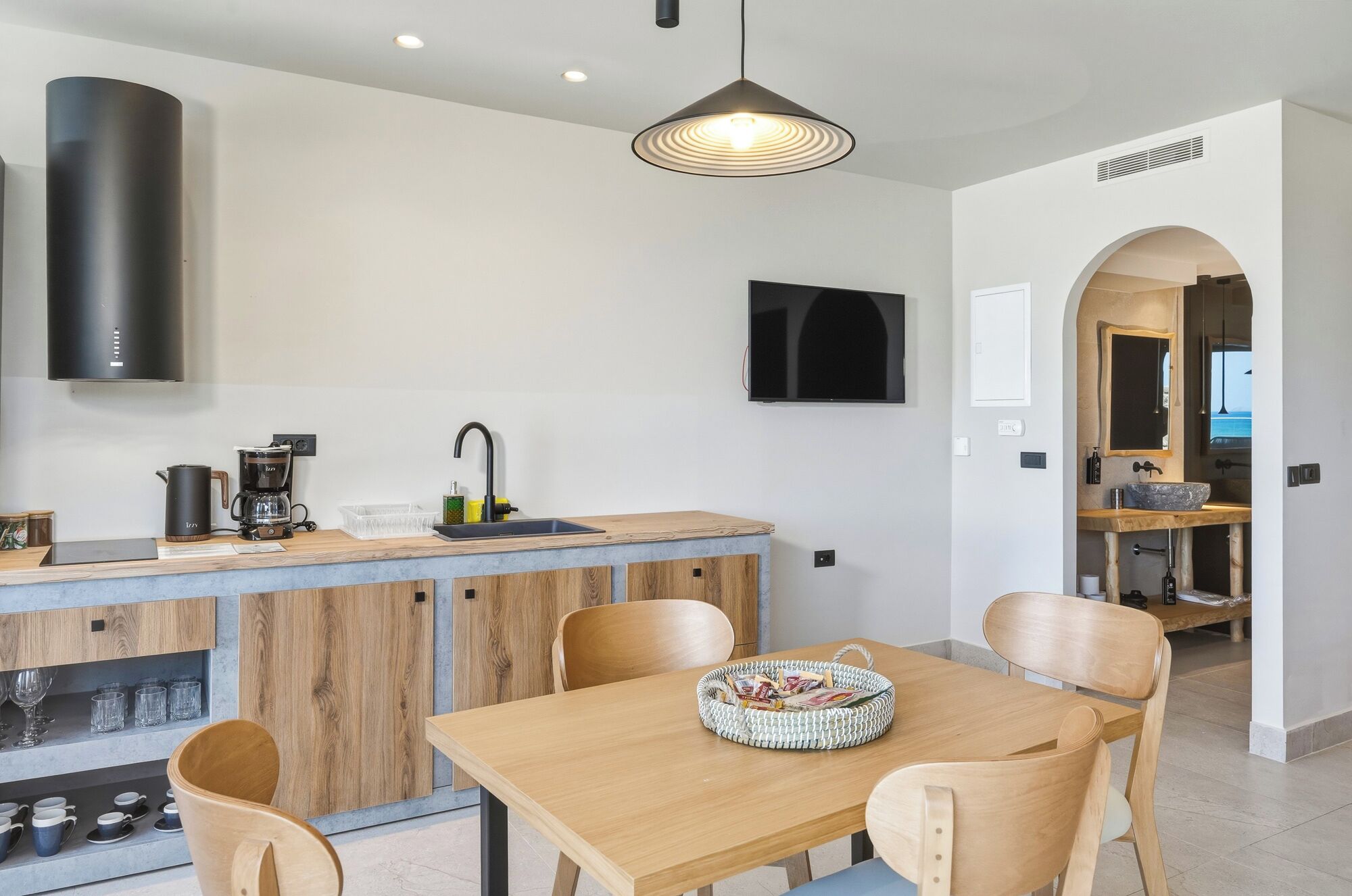 A modern kitchen with a wooden dining table, chairs, and a coffee machine.