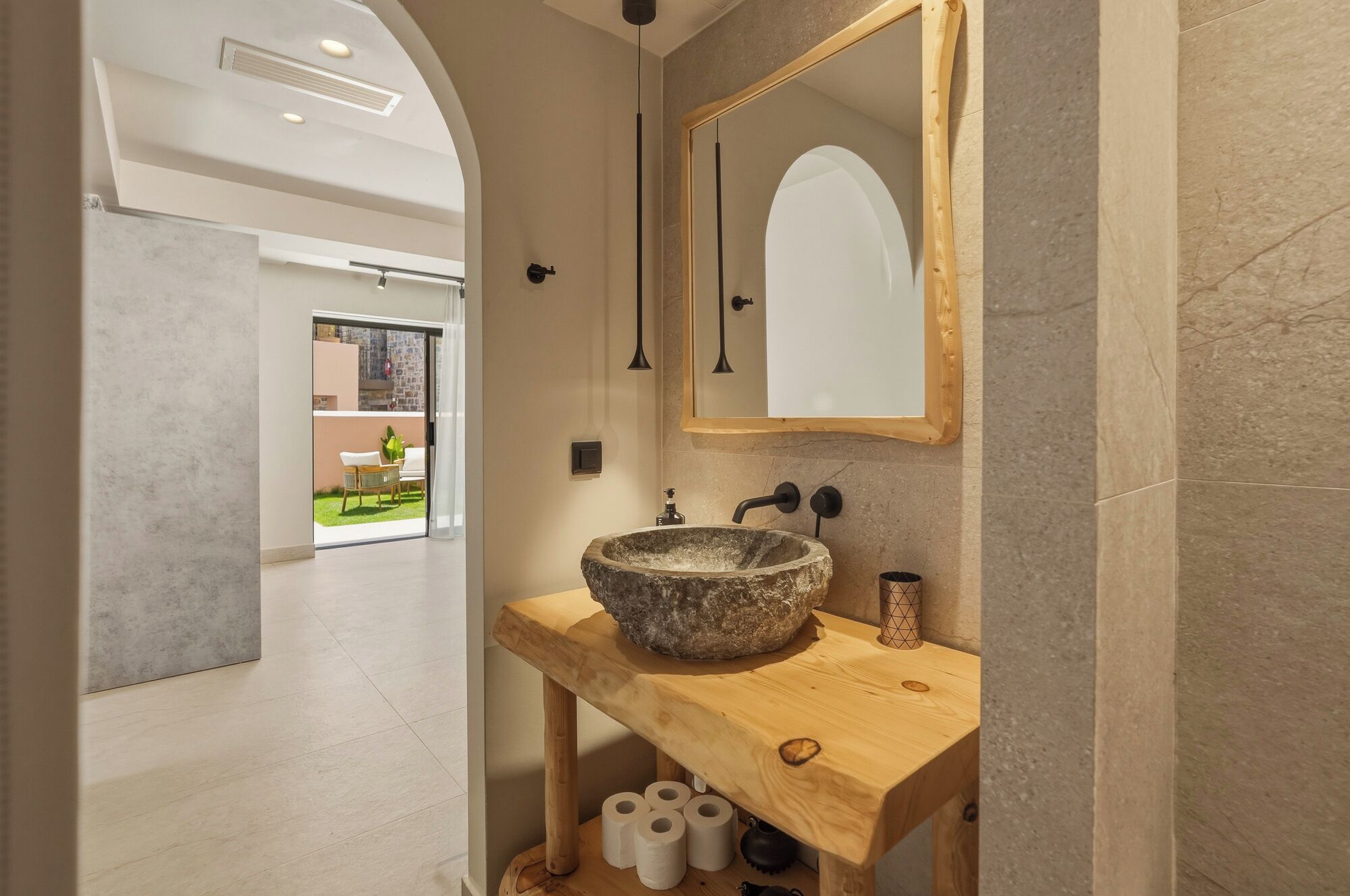 Une salle de bain avec un lavabo en pierre, un meuble-lavabo en bois et un grand miroir.