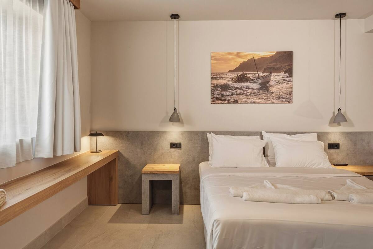 Une chambre à coucher avec un lit, des tables de chevet, une commode, une fenêtre avec des rideaux et un tableau au mur.