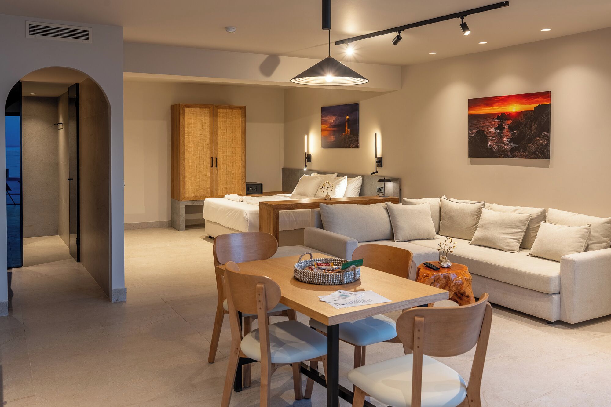 Una habitación de hotel moderna con comedor, sofá y un cuadro en la pared.