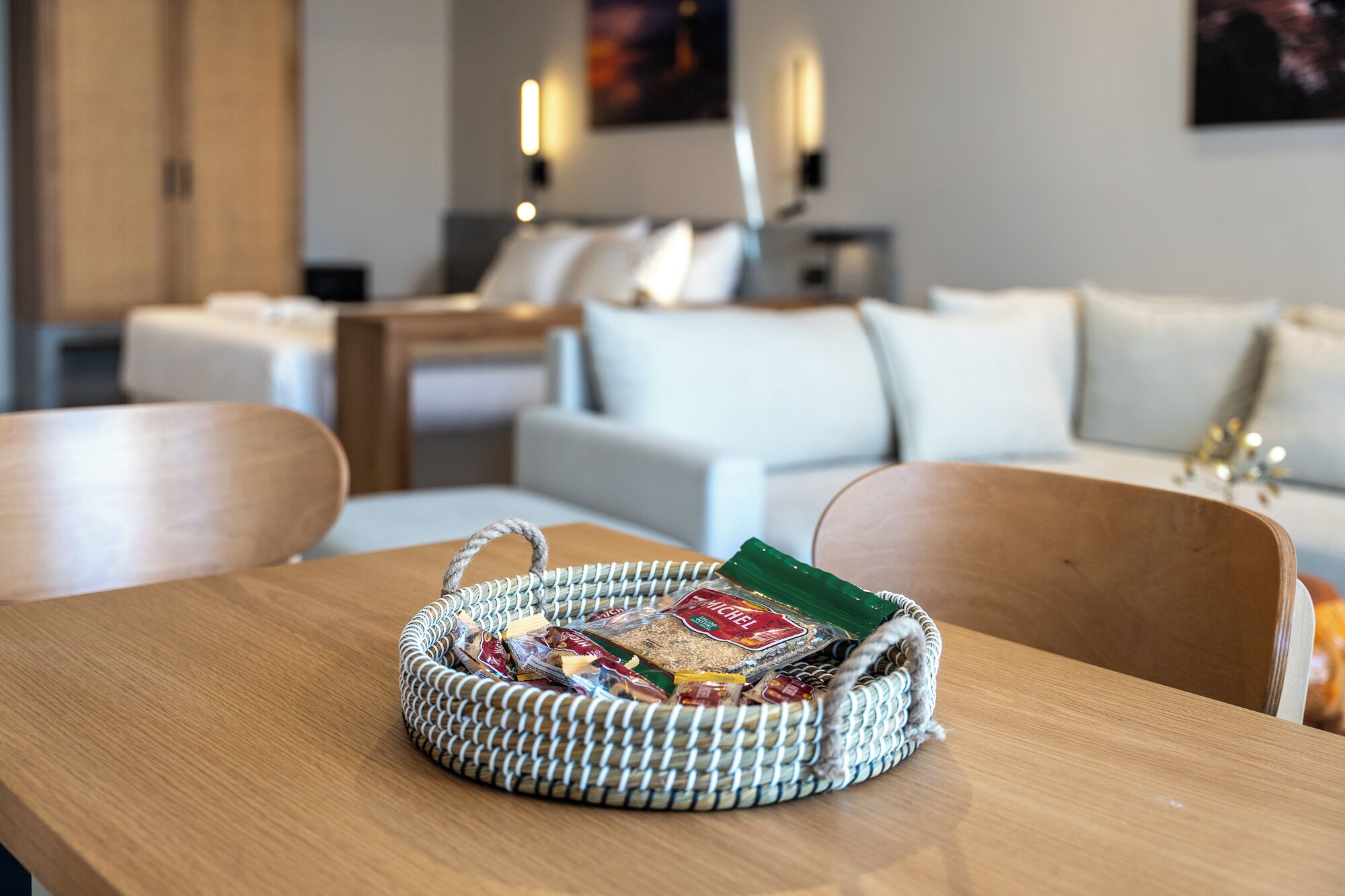 A wicker basket with snacks on a wooden table in a modern living room with a sofa and a coffee table.