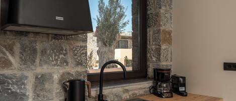 Una cocina con pared de piedra, ventana con vistas, grifo moderno y cafetera.