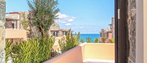 A poolside view with a clear view of the sea, a stone building, and a tree.