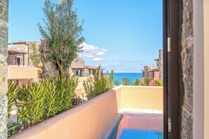 Une vue sur la piscine, avec une vue dégagée sur la mer, un bâtiment en pierre et un arbre.