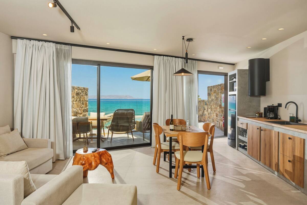 Un salon moderne comprenant un coin repas, une cuisine et offrant une vue sur la mer.