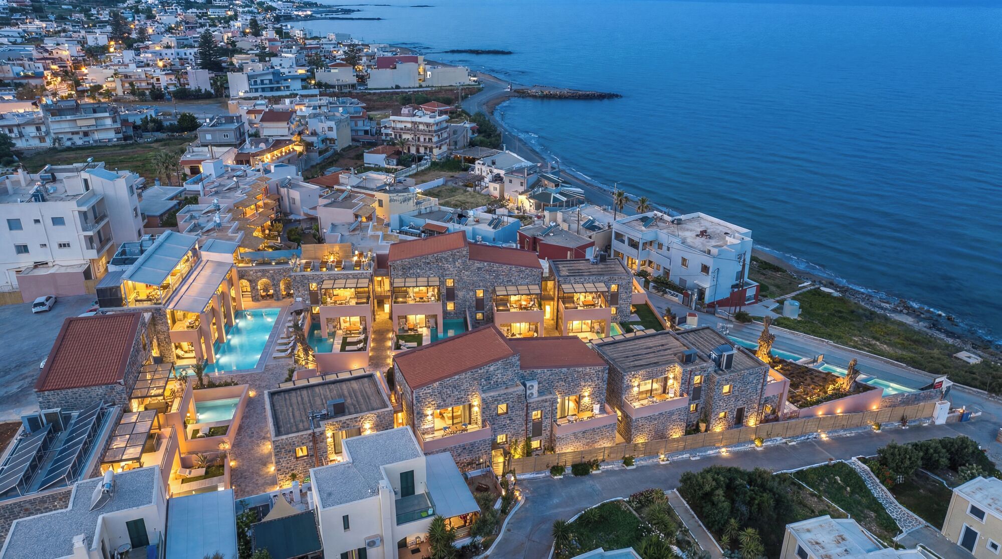 A coastal resort with multiple buildings, a swimming pool, and a view of the sea.