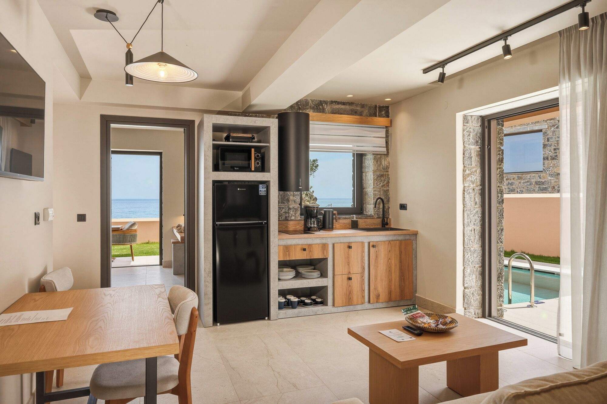 Une cuisine moderne avec vue sur la mer, un coin repas avec une table et des chaises, et un balcon avec une piscine.