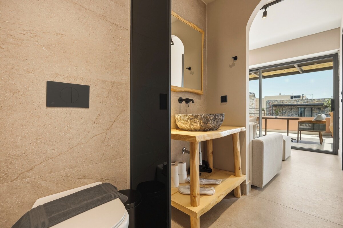 A modern bathroom with a stone sink, wooden vanity, and a view of the cityscape.
