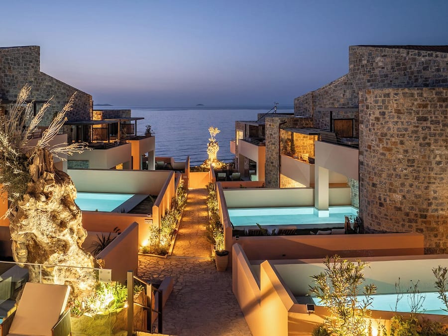 Ein Resort mit mehreren Schwimmbecken, Steingebäuden und Meerblick.