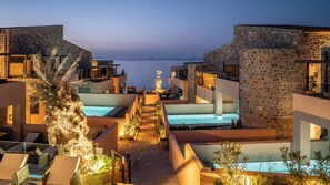 Un resort con diverse piscine, edifici in pietra e vista sul mare.