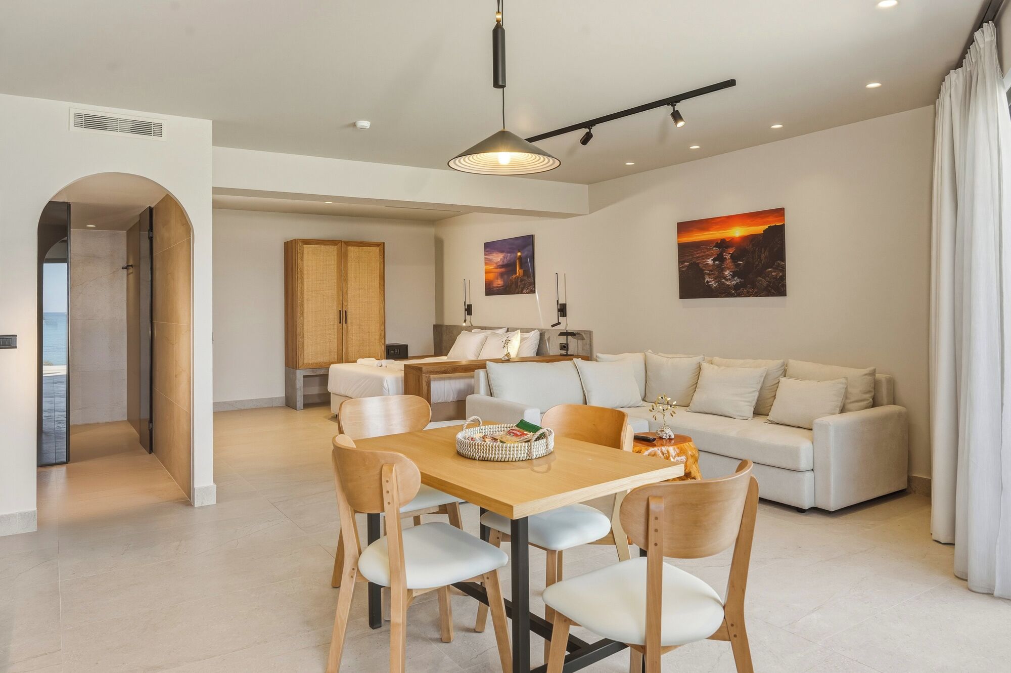 A modern interior with a dining area, a sofa, and artwork on the walls.