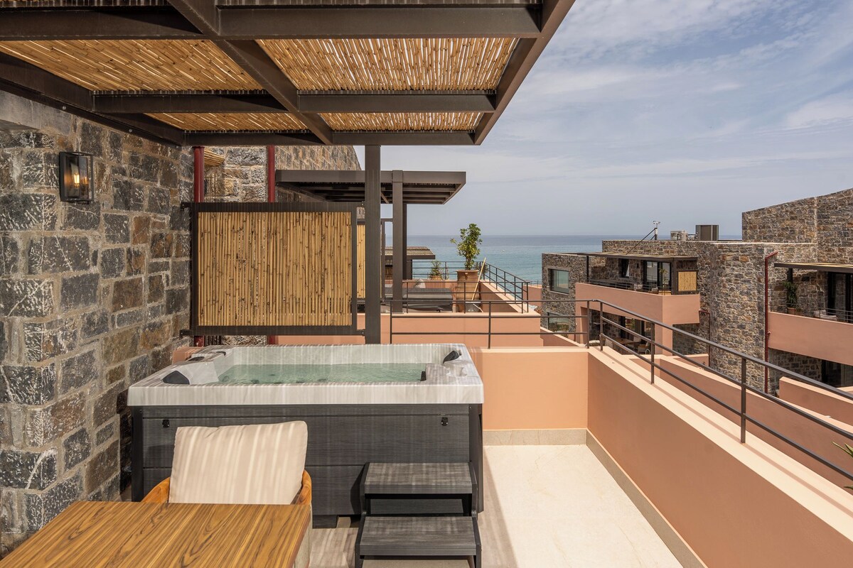 Eine Dachterrasse mit Whirlpool, Sitzgelegenheiten und Meerblick.