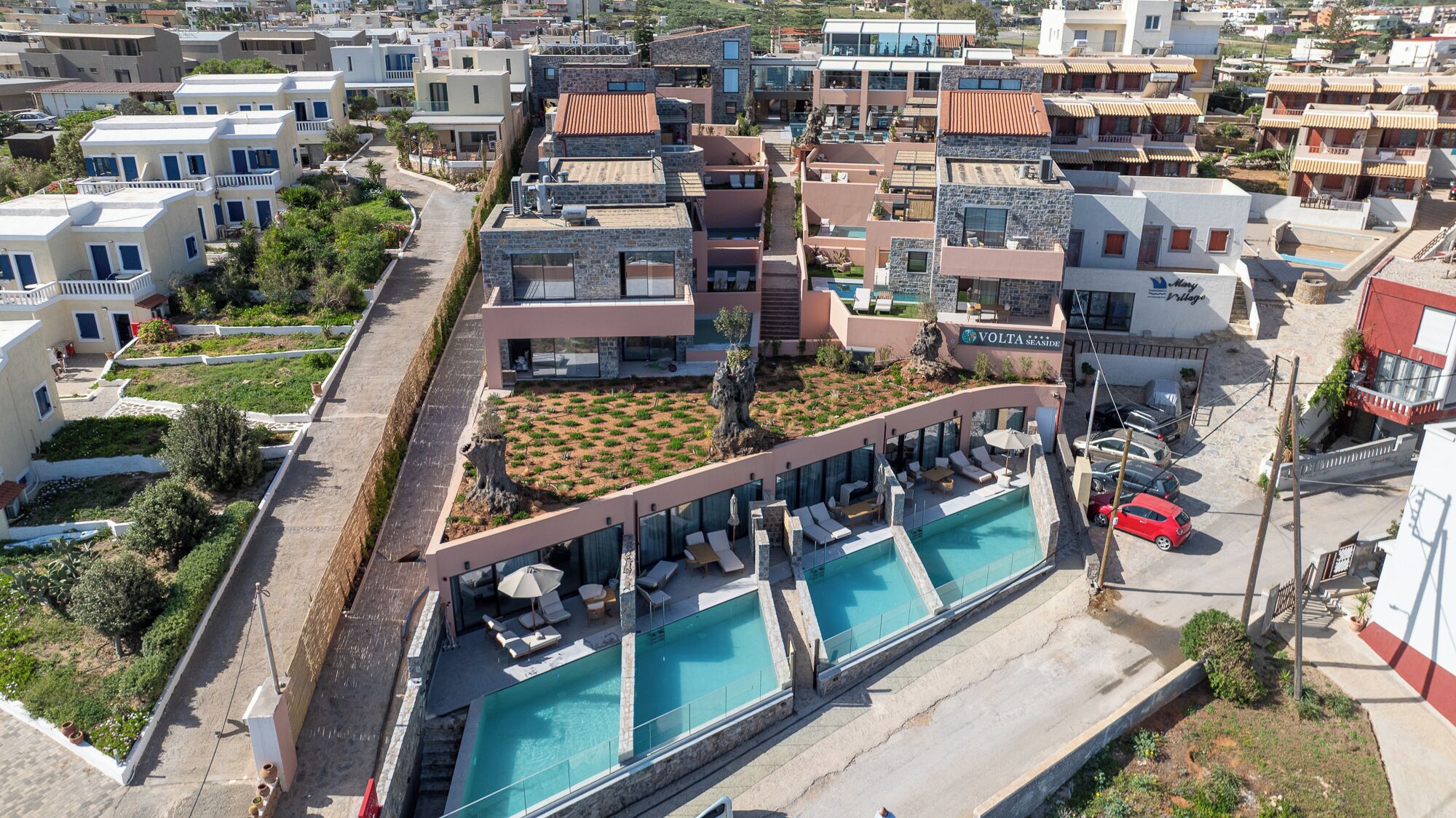 A modern hotel with a rooftop pool, multiple balconies, and a landscaped garden area.