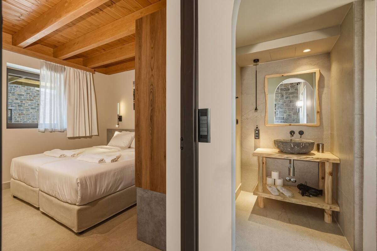 Une chambre à coucher avec un lit, une fenêtre avec des rideaux, une table de chevet et un plafond en bois.