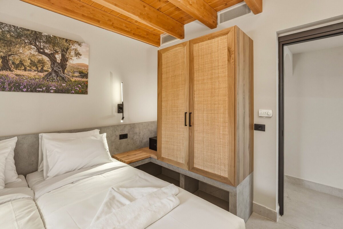 Ein Schlafzimmer mit Bett, Kleiderschrank, Nachttisch, Wandlampe und einem Gemälde.