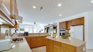 A modern kitchen with wooden cabinets, a large island, and built-in appliances. - Resort Perks & Office! spacious Palm Springs Home (Palm Springs)