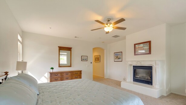 A bedroom with a large bed, a ceiling fan, a fireplace, and a dresser. - Resort Perks & Office! spacious Palm Springs Home (Palm Springs)