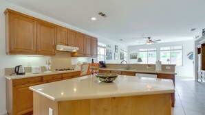 A modern kitchen with wooden cabinets, a large island, and a view of the outdoors. - Resort Perks & Office! spacious Palm Springs Home (Palm Springs)