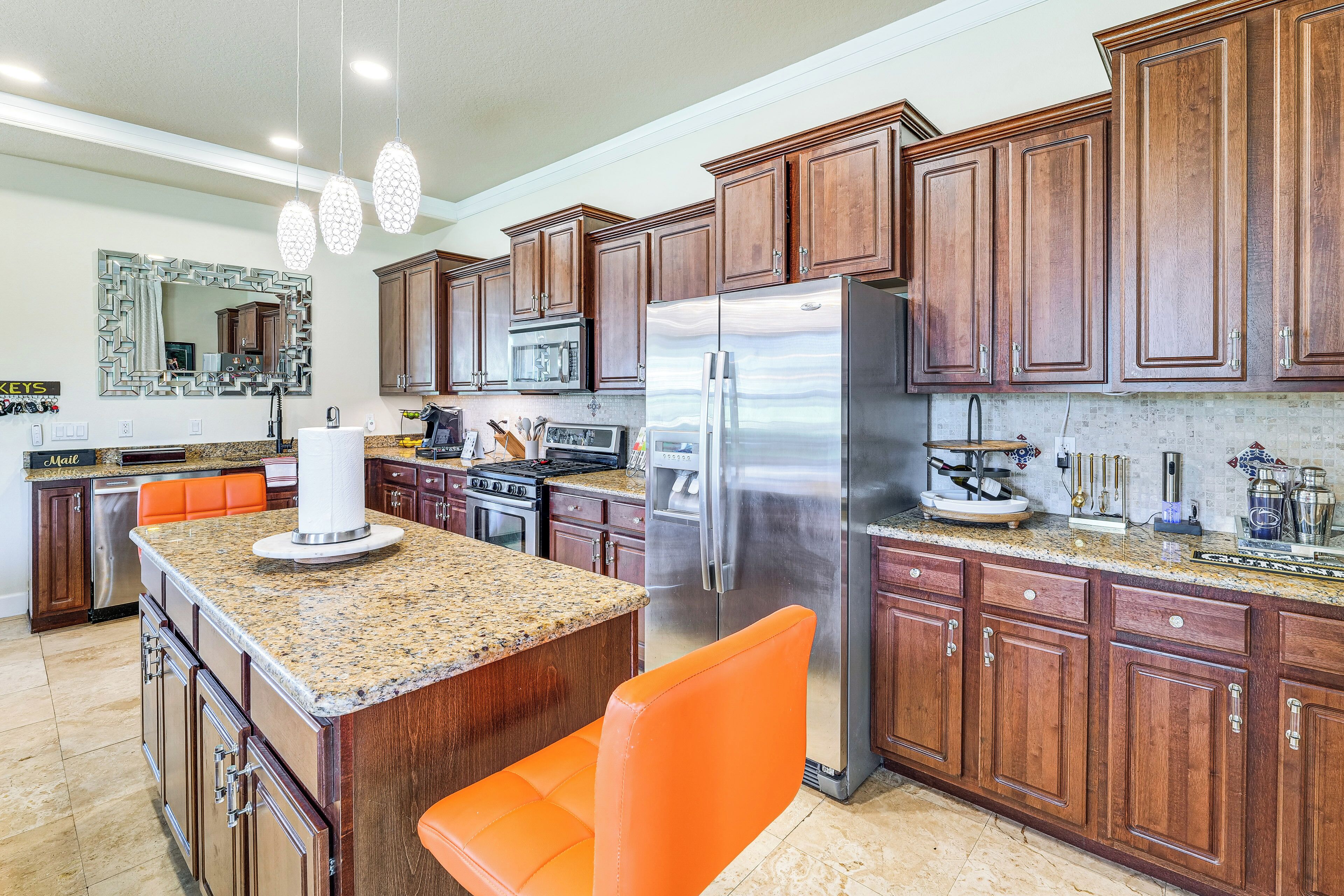 A modern kitchen with wooden cabinets, stainless steel appliances, and a granite countertop.