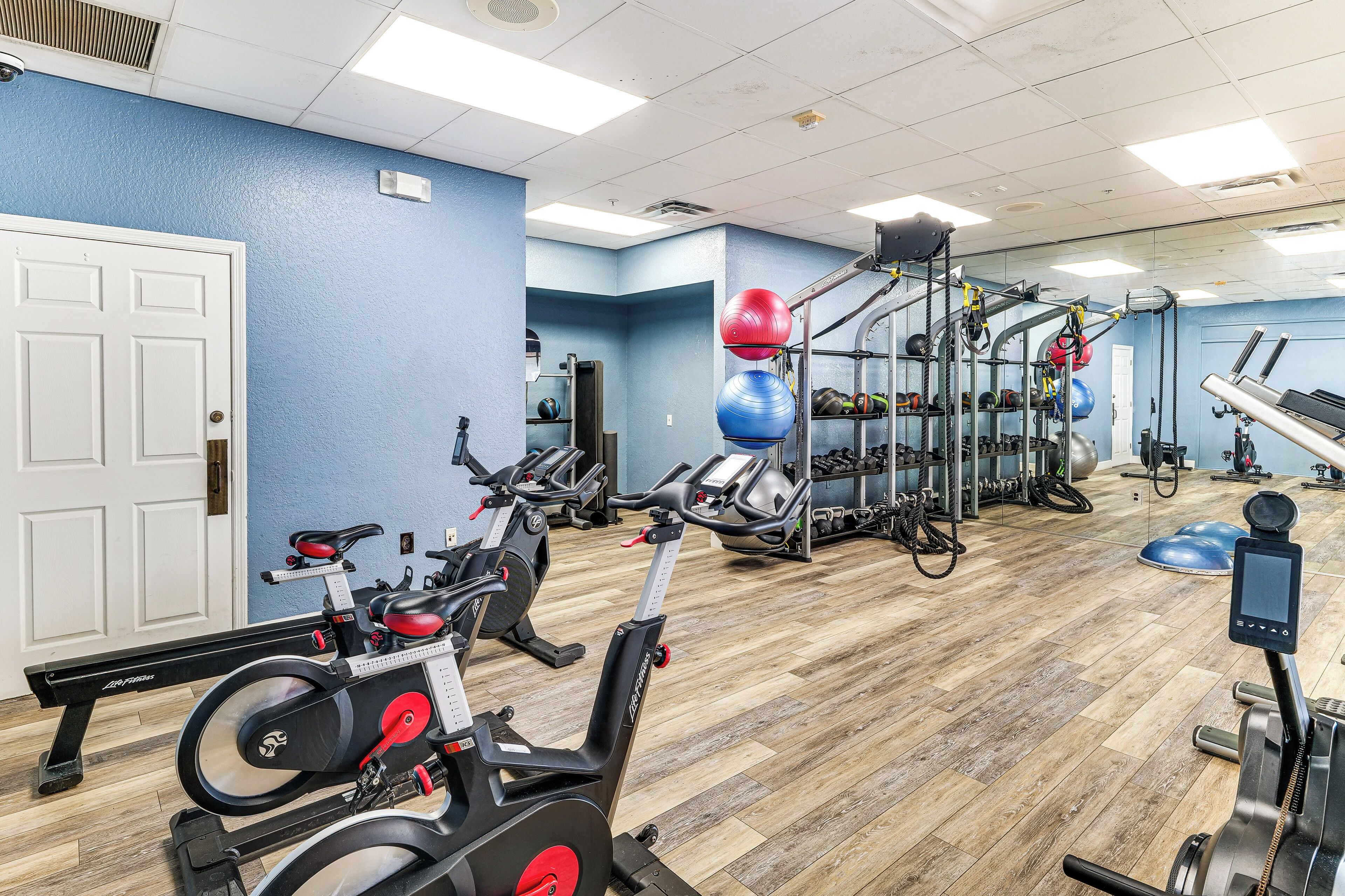 Une salle de sport équipée de matériel d’exercice, dotée d’un plancher en bois et d’un mur bleu.