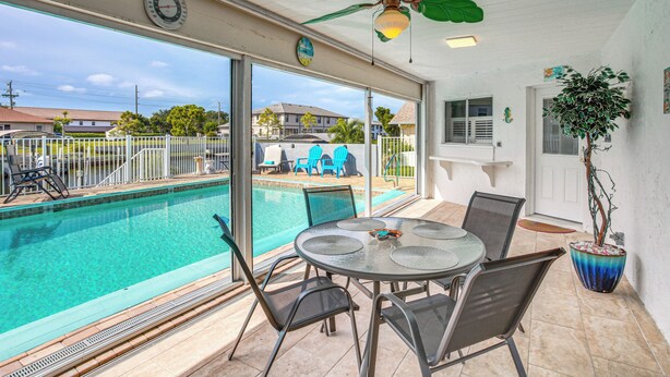 A covered outdoor area with a pool, a table with chairs, and a ceiling fan. - Canal-front, Pet-friendly Cape Coral Retreat! (Cape Coral)