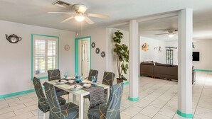 A dining area with a table set for four, chairs with geometric patterns, a ceiling fan, and a view into the kitchen. - Canal-front, Pet-friendly Cape Coral Retreat! (Cape Coral)