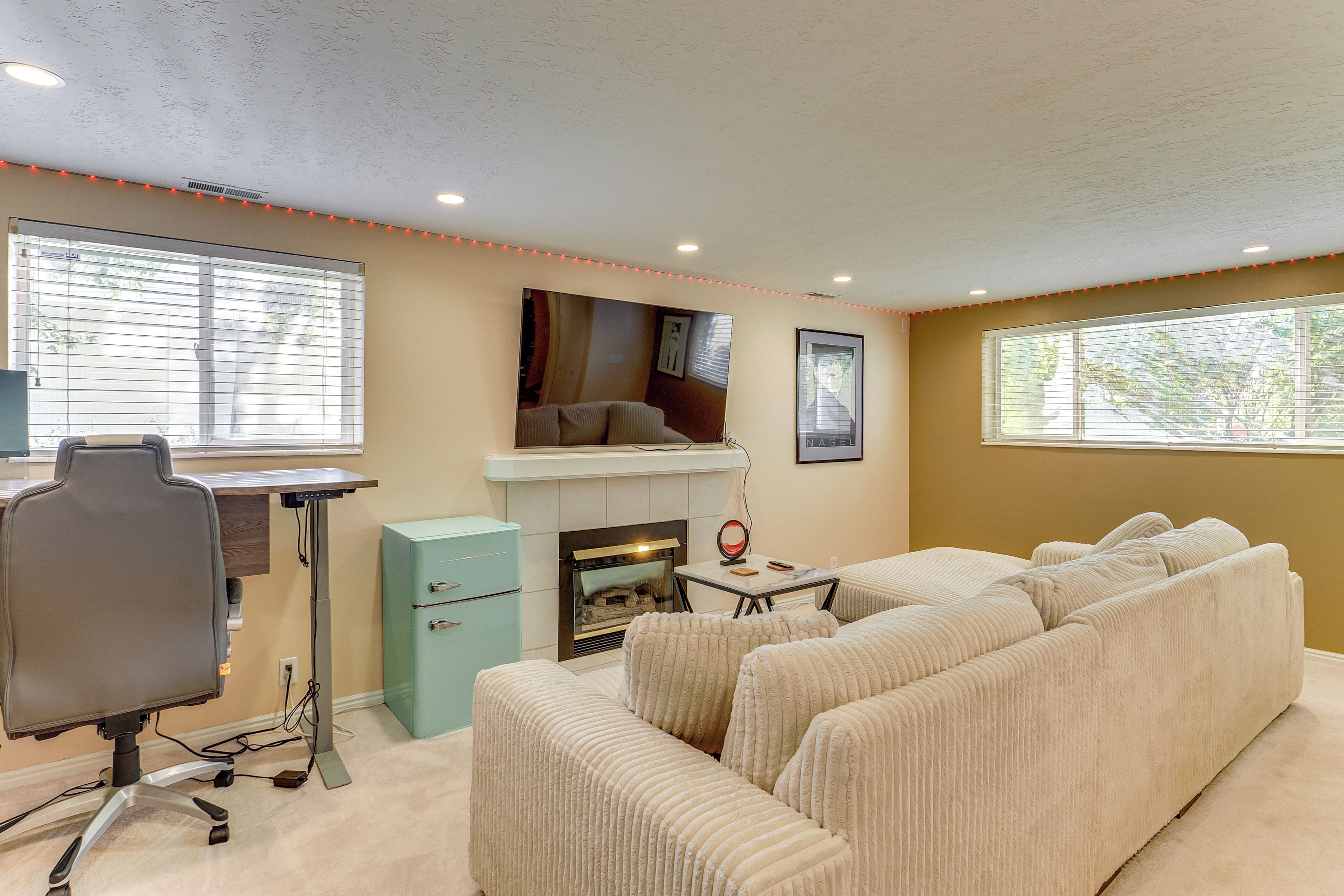 A living room with a sofa, a fireplace, a desk, and a chair.